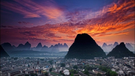 cone shaped mountains around a city at sunset - clouds, sunset, cones, city, mountains