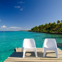 Chairs on Decking overlooking clear blue lagoon and beach at Fakarava Island, French Polynesia