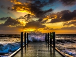 fishing pier in rough sea at sunset