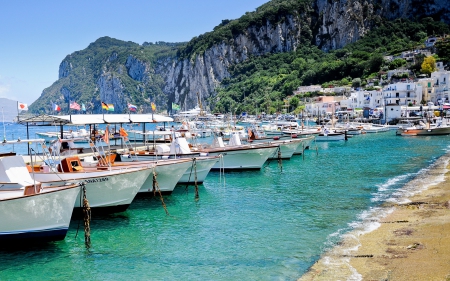 row of boats by a magnificent seaside town - cliff, town, beach, harbor, mountain, boats