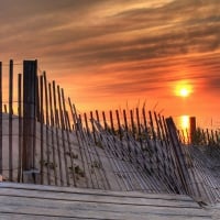 bent fence on a beach sand dune at sunset hdr