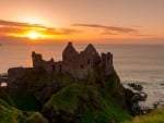 the ruins of dunluce castle in ireland at sunset