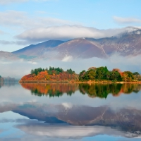 mountains, forest and clouds reflected in a lake