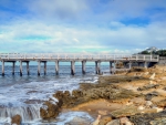 coastal pier under a lighthouse on a hill