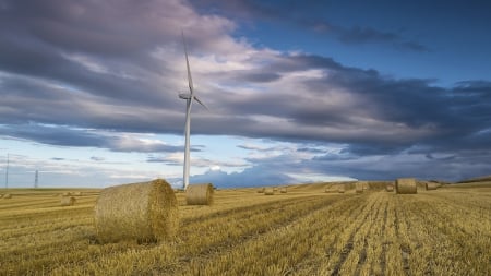 turbine in the middle of a hay field - turbine, hay, filed, clouds, bales