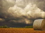 beautiful storm clouds over a field of hay bales