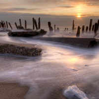 broken pier on a beach at sunset