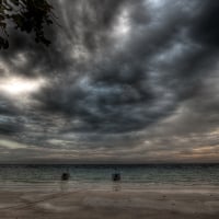 boats tied up on a beach under stormy sky hdr