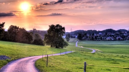 winding road down to a valley town - town, road, valley, fields, trees, grass