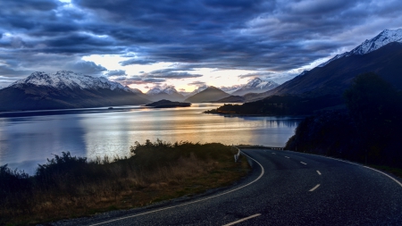 blacktop road down to a lake at sundown - clouds, blacktop, sundown, road, lake, mountains