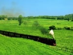 old train steaming through green fields