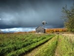 barn and windmill under stormy clouds