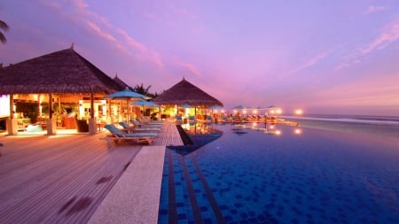 a seaside infinity pool in a resort at dusk - pool, lights, dusk, seaside, resort