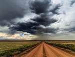 long dirt road under storm clouds