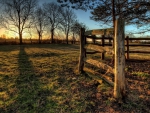 a wooden fence in a field at sunrise hdr