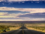 long blacktop highway through the prairie