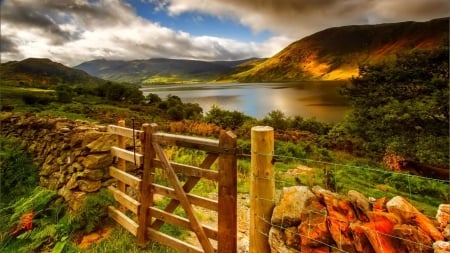 gate in a fence on a hill above a lake