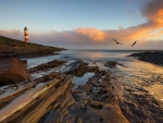 lighthouse above a rocky sea inlet