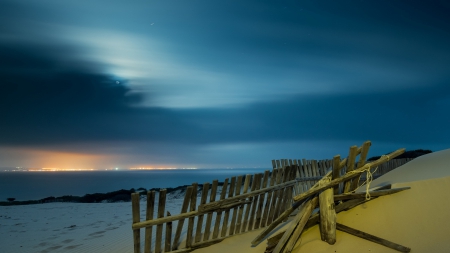 broken fence on a beach at night - fence, beach, broken, dune, city, night, sea, lights