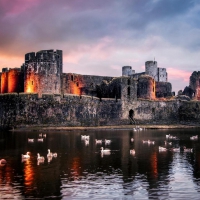 castle surrounded by a lake at sunset