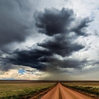 long dirt road under stormy skies