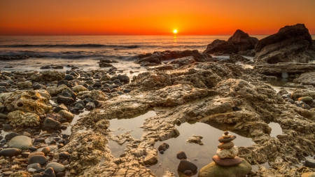 stone pile on a rocky seashore at sunset - pile, shore, sunset, sea, stones, rocks