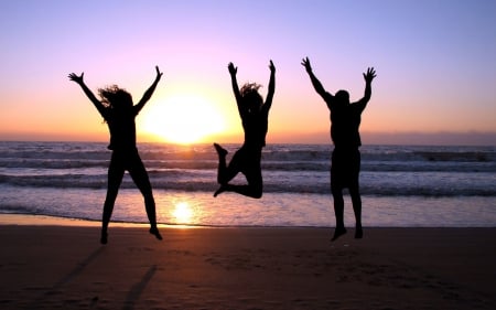 silhouettes jumping on a beach at sunset - silhouettes, people, beach, sunset, sea