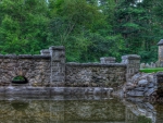 stone wall reflected in a pond hdr