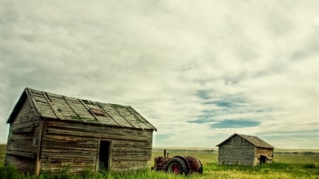 tractor parked between old shacks - clouds, farm, tractor, shacks