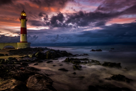 The Lighthouse - sky, ocean, lighthouse, sunset, rocks, nature, clouds, splendor, ocean view, sea