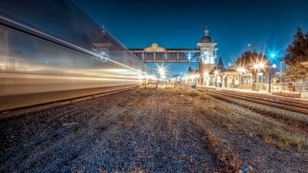 train passing a station at night in long exposure hdr