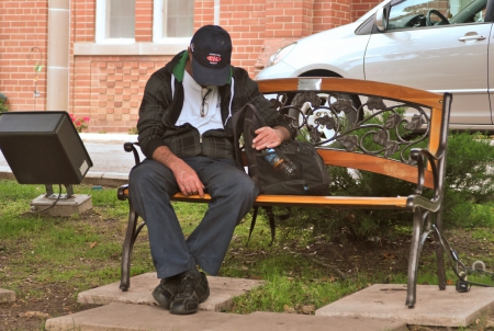 Homeless man sleeping on bench in Brampton Ontario Canada