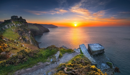 Sunset At Valley Of The Rocks, England - horizon, ocean, sky, cliff, sunset, yellow, clouds, blue, beautiful, orange, green, flowers, grass, coastal, wildflowers