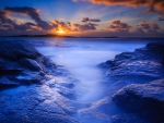 sunrise over blue rocky seashore