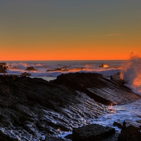 splashing waves on a rocky shore at sunset