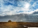 sun rays over a stone cabin on the plains