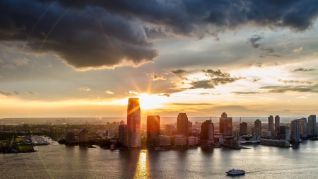 sunset over a cityscape - clouds, rays, city, sunset, sea