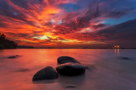 Explosive Clouds During Sunset - beach, sky, sunset, rocks, city lights, yellow, blue, beautiful, clouds, red, orange, sea