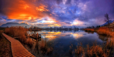 Magic Lights At Sunset - lake, sky, trees, dock, water, mountains, sunset, reeds, tranquility, walkway, yellow, clouds, red, beautiful, orange