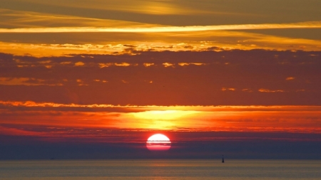 A large yellow sun at sunset - sky, sunset, sea, clouds