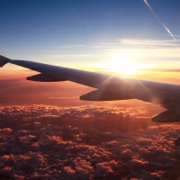 sun over a wing above the clouds