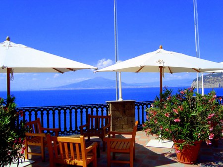 I Can See For Miles - flower pots, chairs, sea, mountains, sky, ocean view, umbrellas