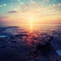 golden sunrise over dark rocky shores