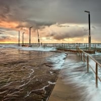 sea waves overflowing pier at sunset hdr