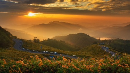 cars along a mountain road at a beautiful sunset - haze, cars, sunset, people, road, mountains