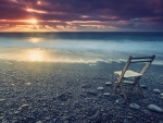 folding chair on a beach at sunset