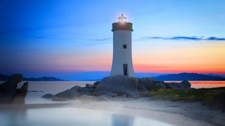 lighthouse with green lamp - beach, lighthouse, green, sunset, lamp, rocks