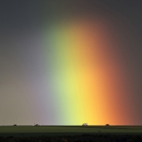 Cars drive under a rainbow