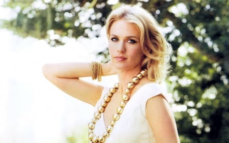 January Jones - trees, blue eyes, blonde, large beaded gold necklace, sleeveless top