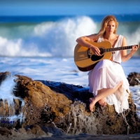 girl strumming guitar in a sea cliff